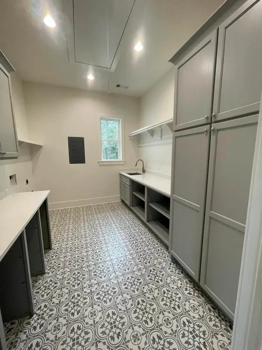 Utility room with tall gray shaker cabinets, a folding counter, a utility sink and black-and-white patterned floor tile