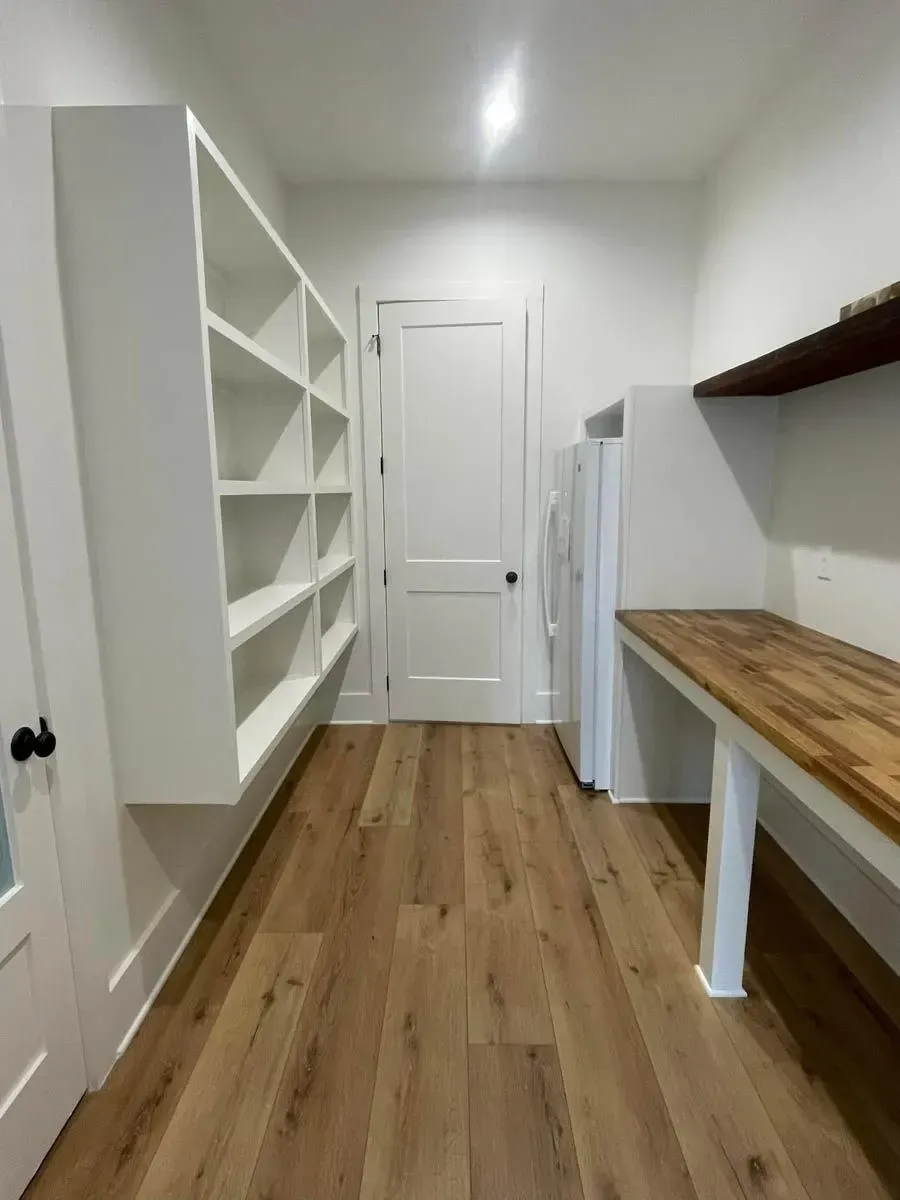 Walk-in pantry with tall white open shelving, a butcher-block counter, oak floors and space for a second refrigerator