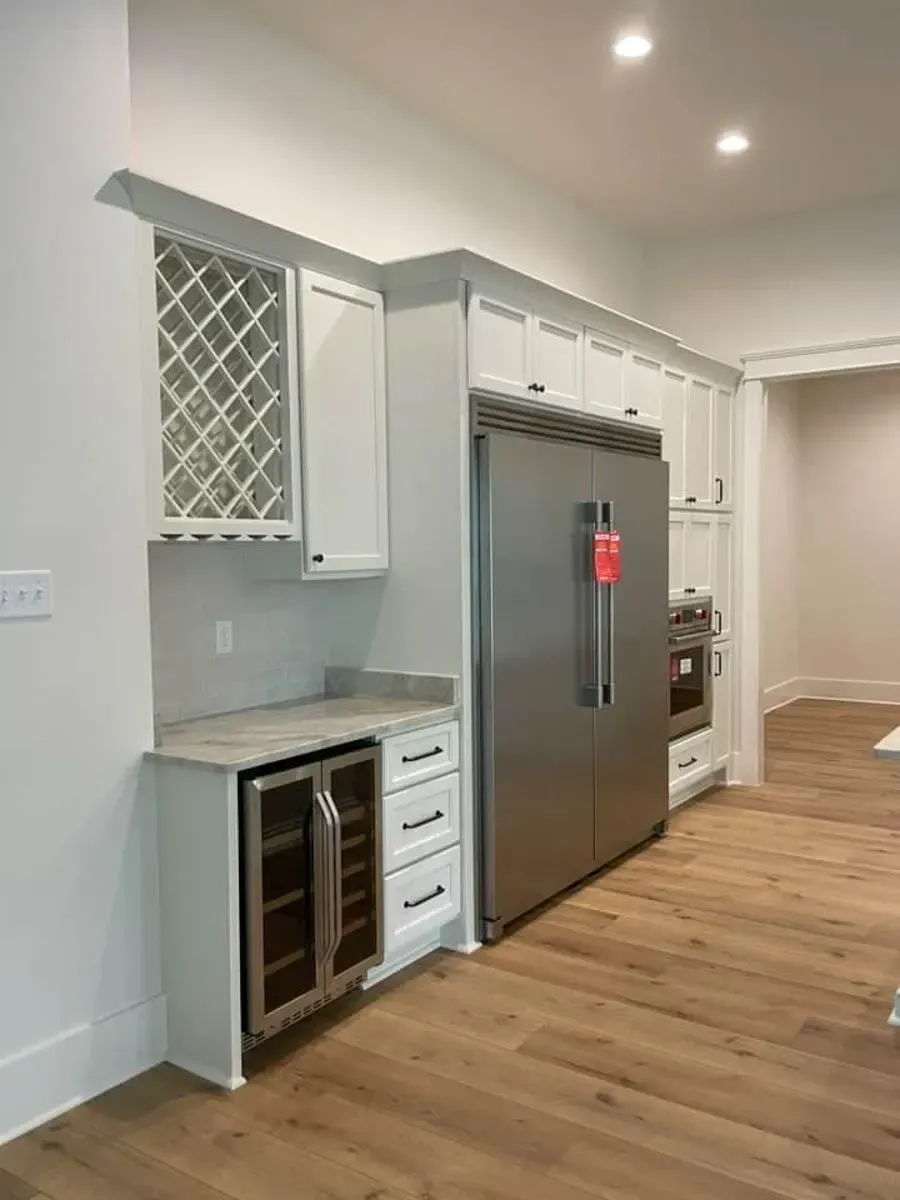 Beverage station with a wine lattice, an undercounter wine fridge, a built-in refrigerator column and wall ovens