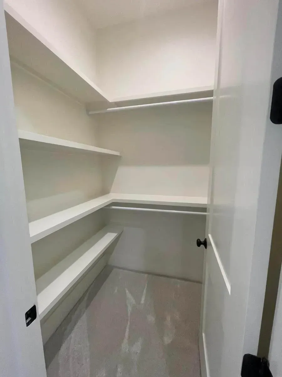 Secondary bedroom walk-in closet with white wraparound shelving