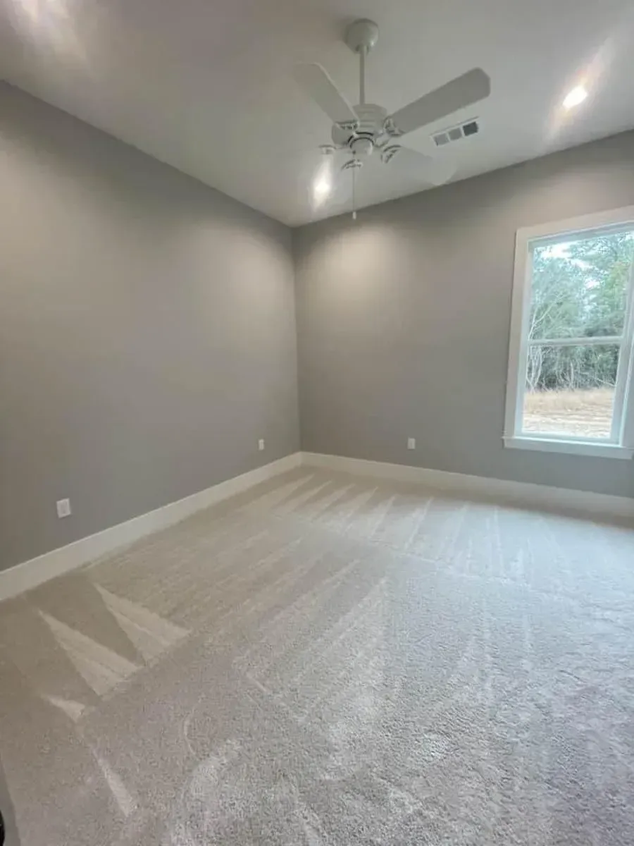 Bedroom 4 with carpet, a ceiling fan and a window near the garage side of the house