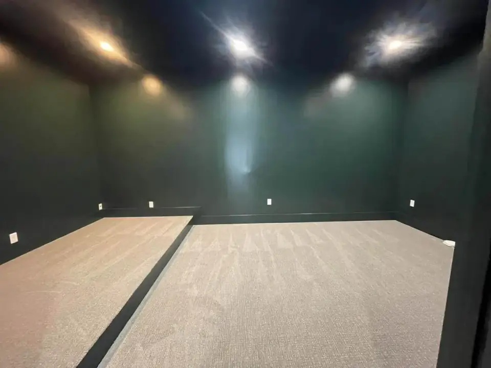 Home theater room with deep green walls, a dark ceiling, recessed lights and a carpeted raised platform for a second row of seats