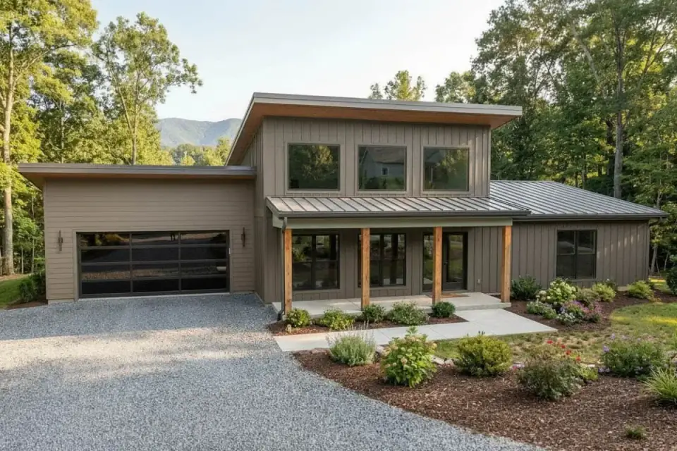 Modern barndominium exterior with stacked shed rooflines at varying heights, dark horizontal metal siding paired with light wood-look accent panel on upper volume, black metal standing-seam roof, prominent covered front porch with painted columns, large vertical windows