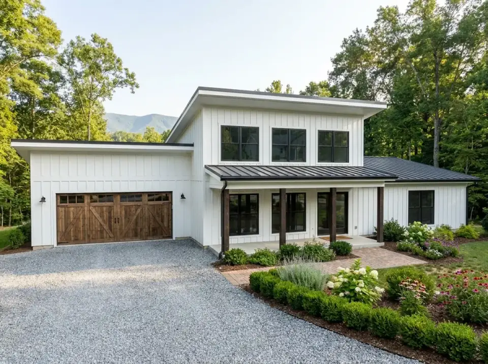 High-Contrast Modern Farmhouse facade variant with classic white board-and-batten exterior sharply contrasted by black window frames black fascia and dark standing-seam metal roof, dark stained wood garage door and porch columns, crushed gravel driveway leading to red brick walkway, planting beds with hydrangeas coneflowers and ornamental grasses