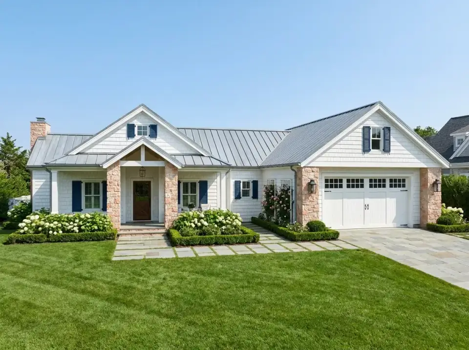 Coastal Shingle Traditional facade variation with white cedar shingles, blue shutters, warm stone columns, a bluestone walkway and formal boxwood hedges with hydrangea plantings