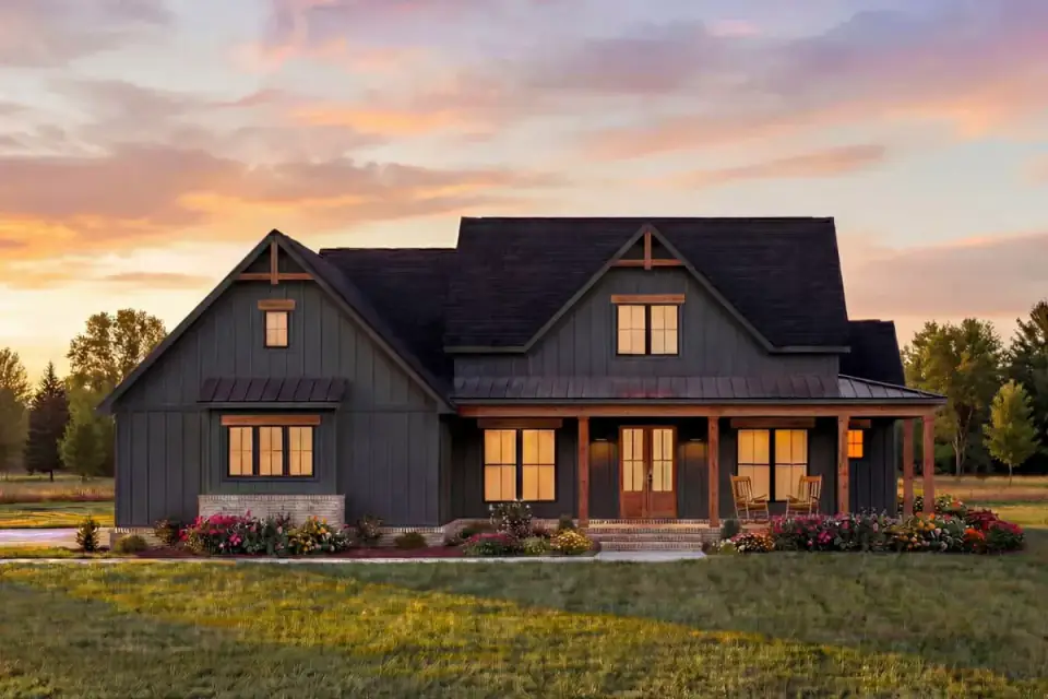 Dusk rendering of the farmhouse exterior with warm interior light spilling through black-framed windows onto the porch