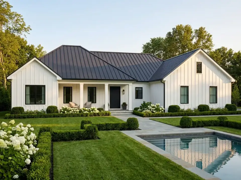 White board-and-batten modern farmhouse ranch with dark metal roof, black windows, and boxwood parterre